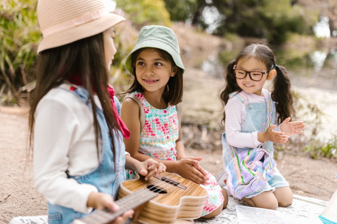 Free Girls Kneeling on a Picnic Blanket Together Stock Photo
